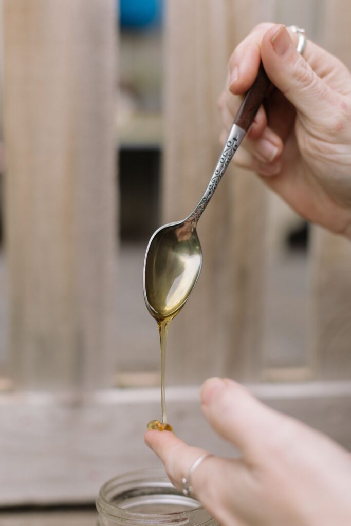 Honey dripping from an ornate spoon onto a fingertip